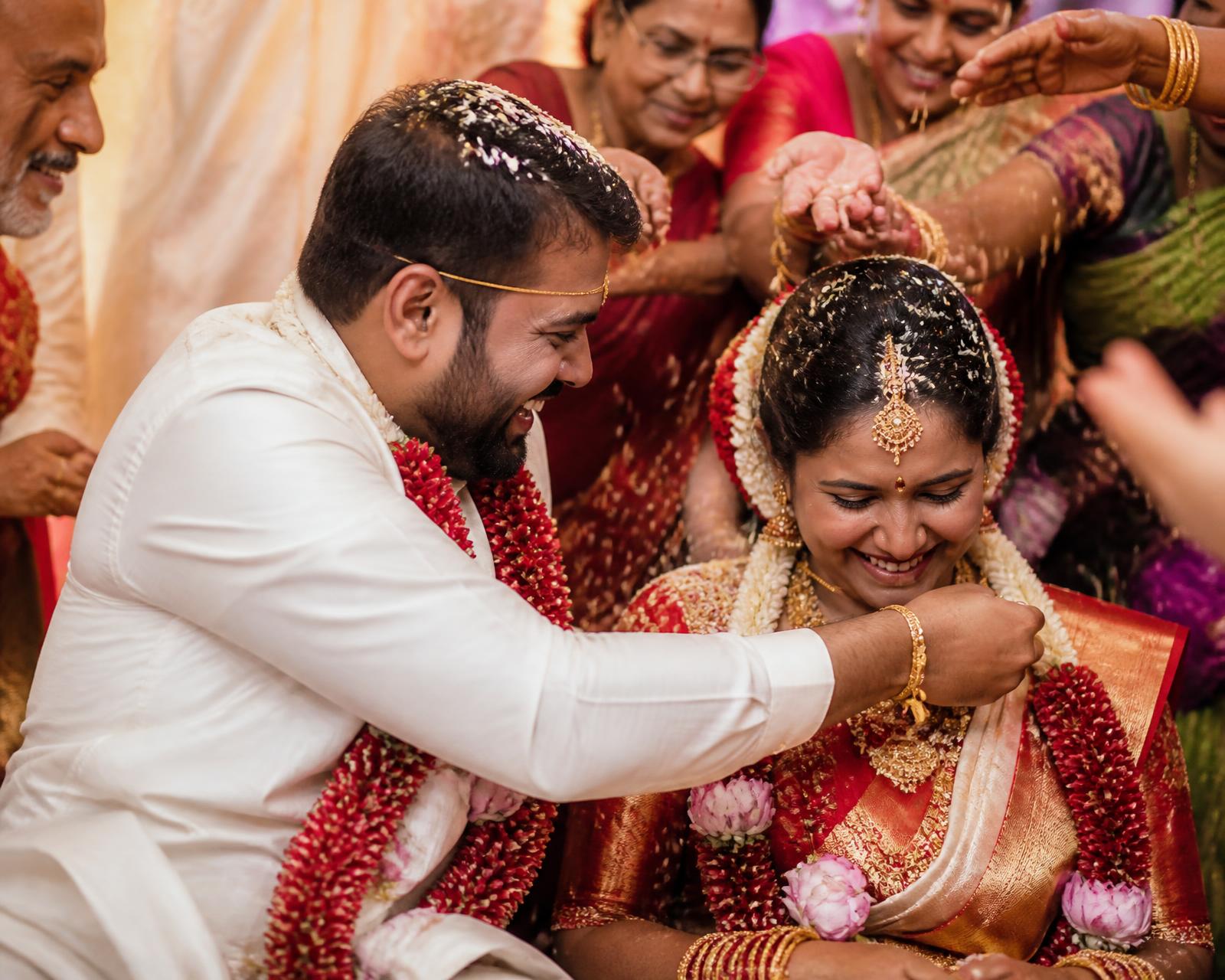 Family showering rice over a bride and groom during a South Indian wedding ritual