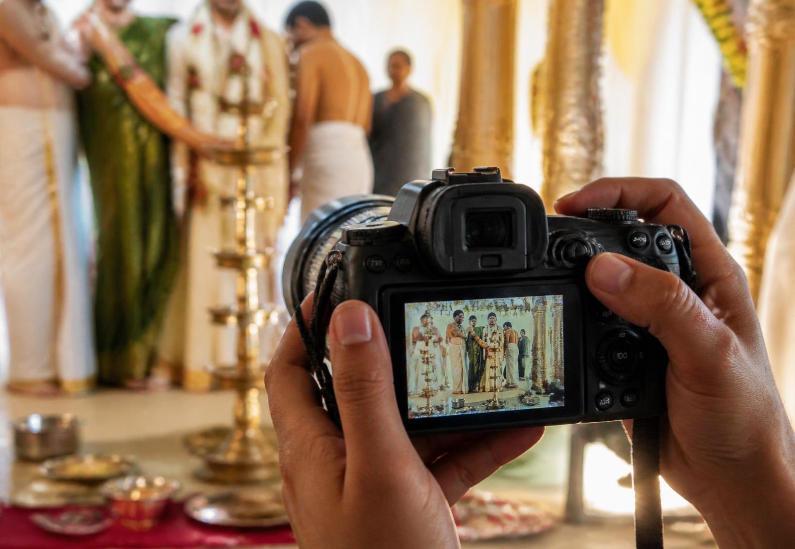 A photographer's hands framing a candid frame during a South Indian ceremony
