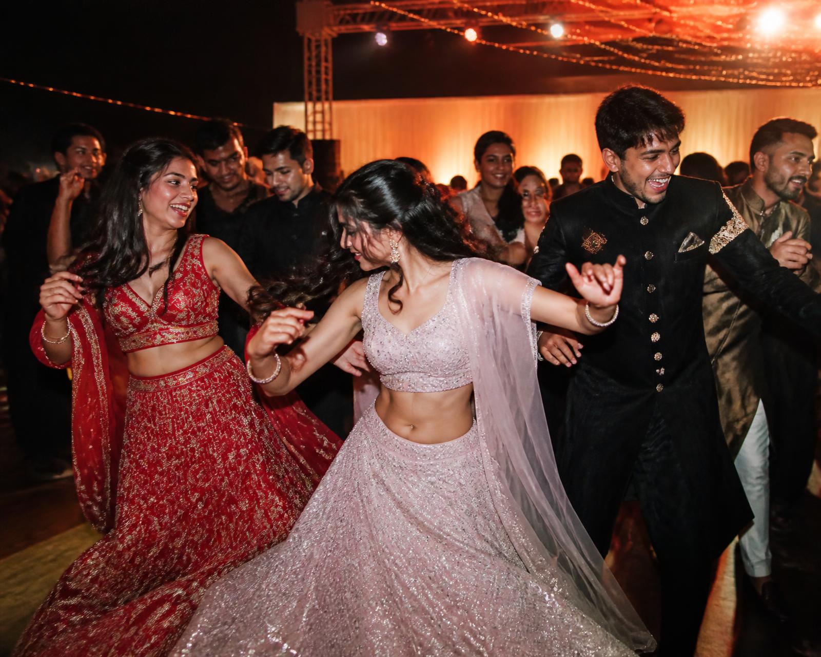 Sangeet dance floor caught mid-movement under warm uplighting